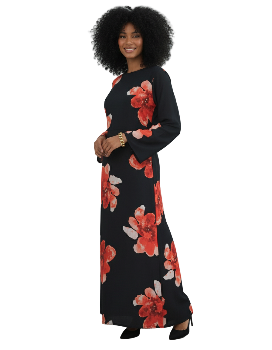 Woman wearing a black dress with red floral pattern against a white paneled wall.