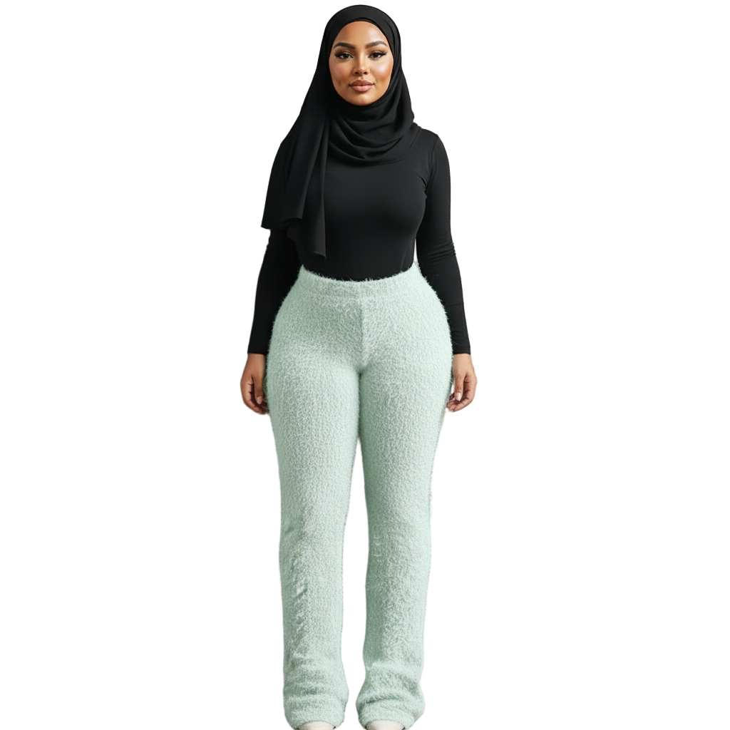 Woman wearing a black top and light blue pants against a textured beige wall.