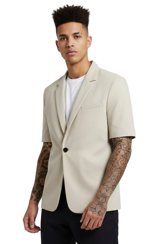 Man wearing a beige blazer over a white shirt on a plain background