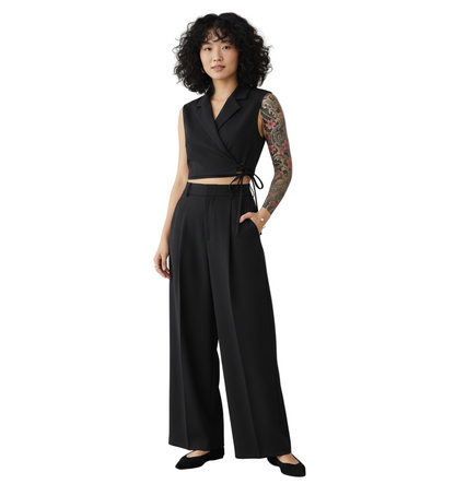 Woman wearing a black sleeveless top and wide-leg pants against a plain background