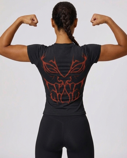 Person wearing a black t-shirt with red tribal design on the back, flexing muscles against a light gray background.