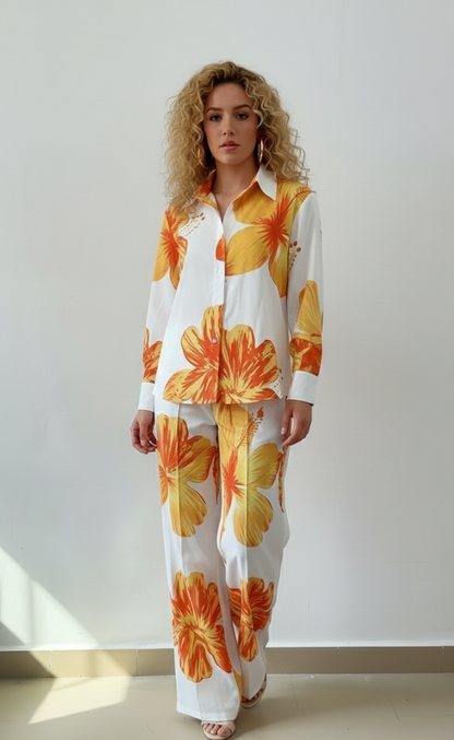 Woman wearing a white outfit with large orange floral patterns against a plain background