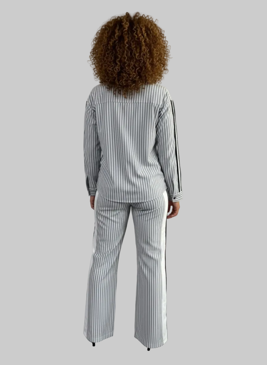 Person wearing a striped outfit standing in a minimalistic room with a plain background.