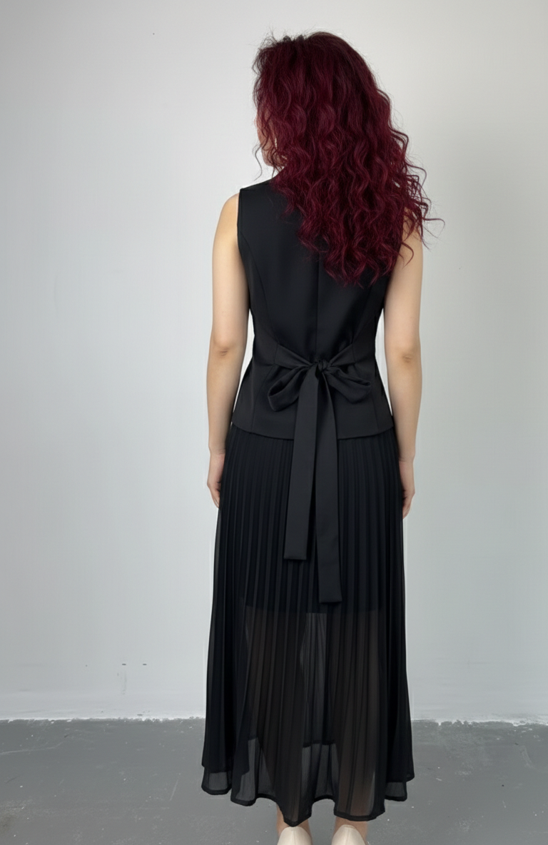 Person wearing a black sleeveless dress with a belt on a plain background