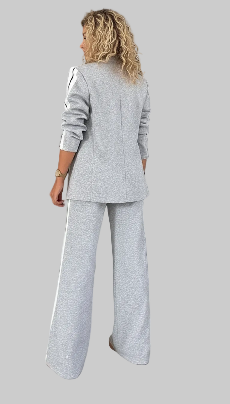 Person wearing a gray suit standing in front of a wardrobe with clothes and shoes.