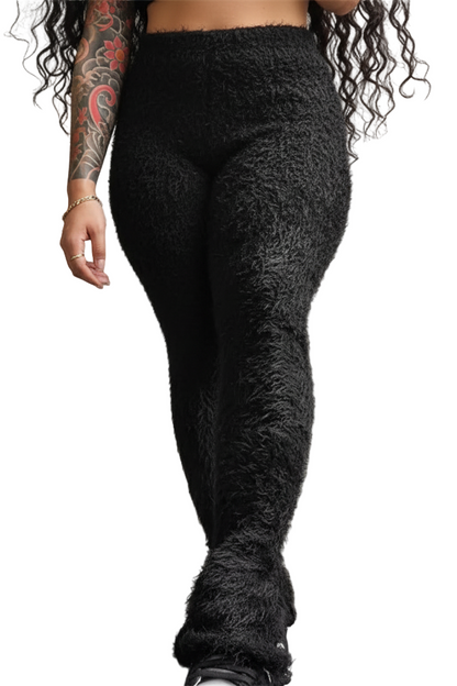 Person wearing black textured pants against a gray wall