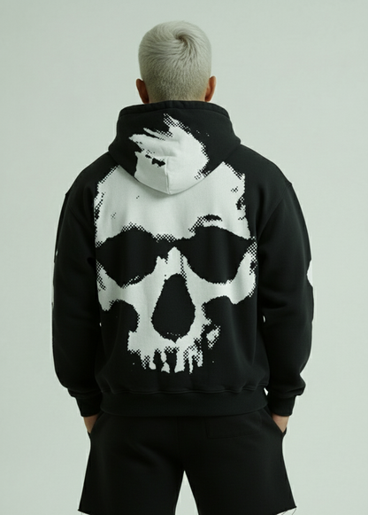 Person wearing a black hoodie with a white skull design on the back against a light gray background