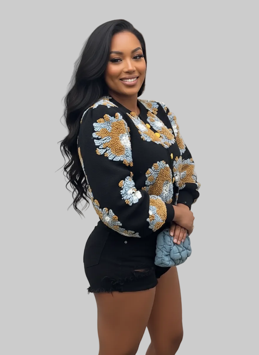 Woman in a floral jacket and black shorts standing indoors.