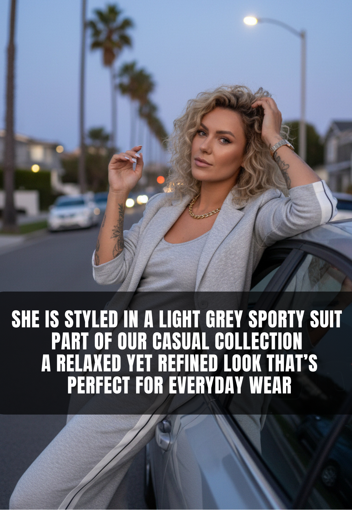 Woman in a light gray sportsuit standing next to a car with palm trees in the background