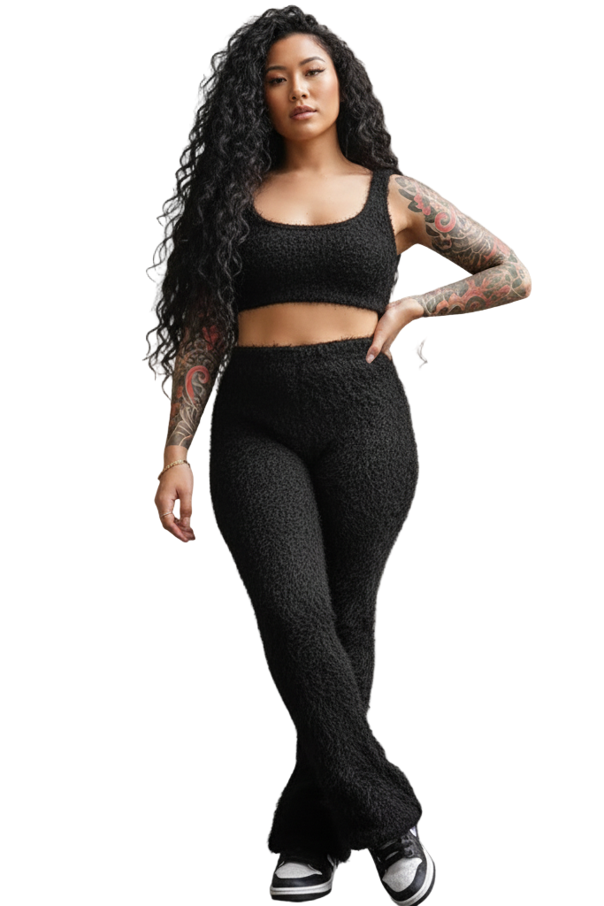 Woman wearing a black knit outfit against a gray wall