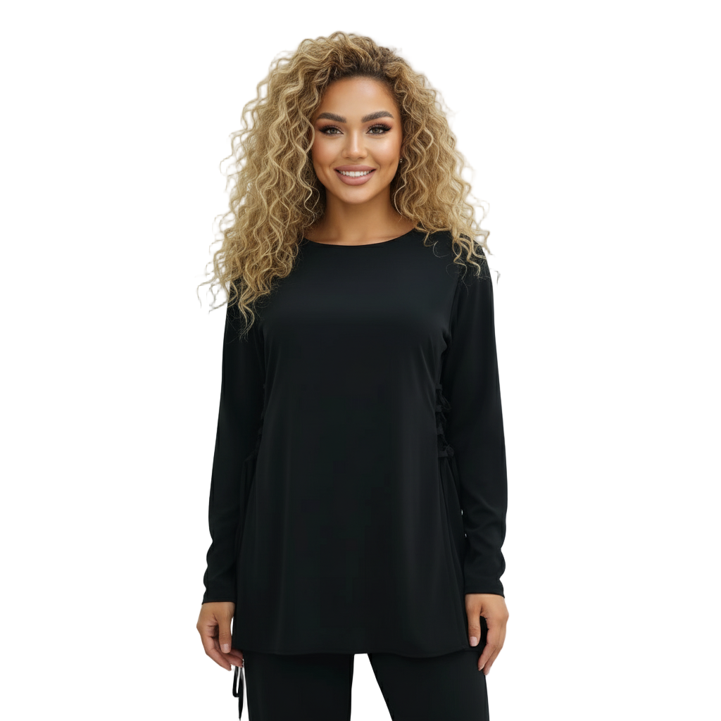 Woman wearing a black long-sleeve top against a white wall