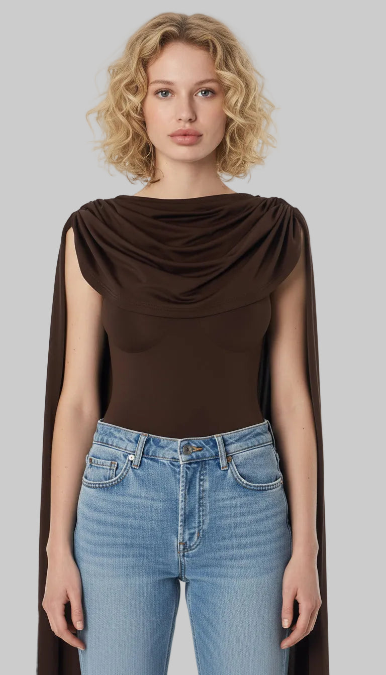 Woman wearing a brown draped top and blue jeans on a white background