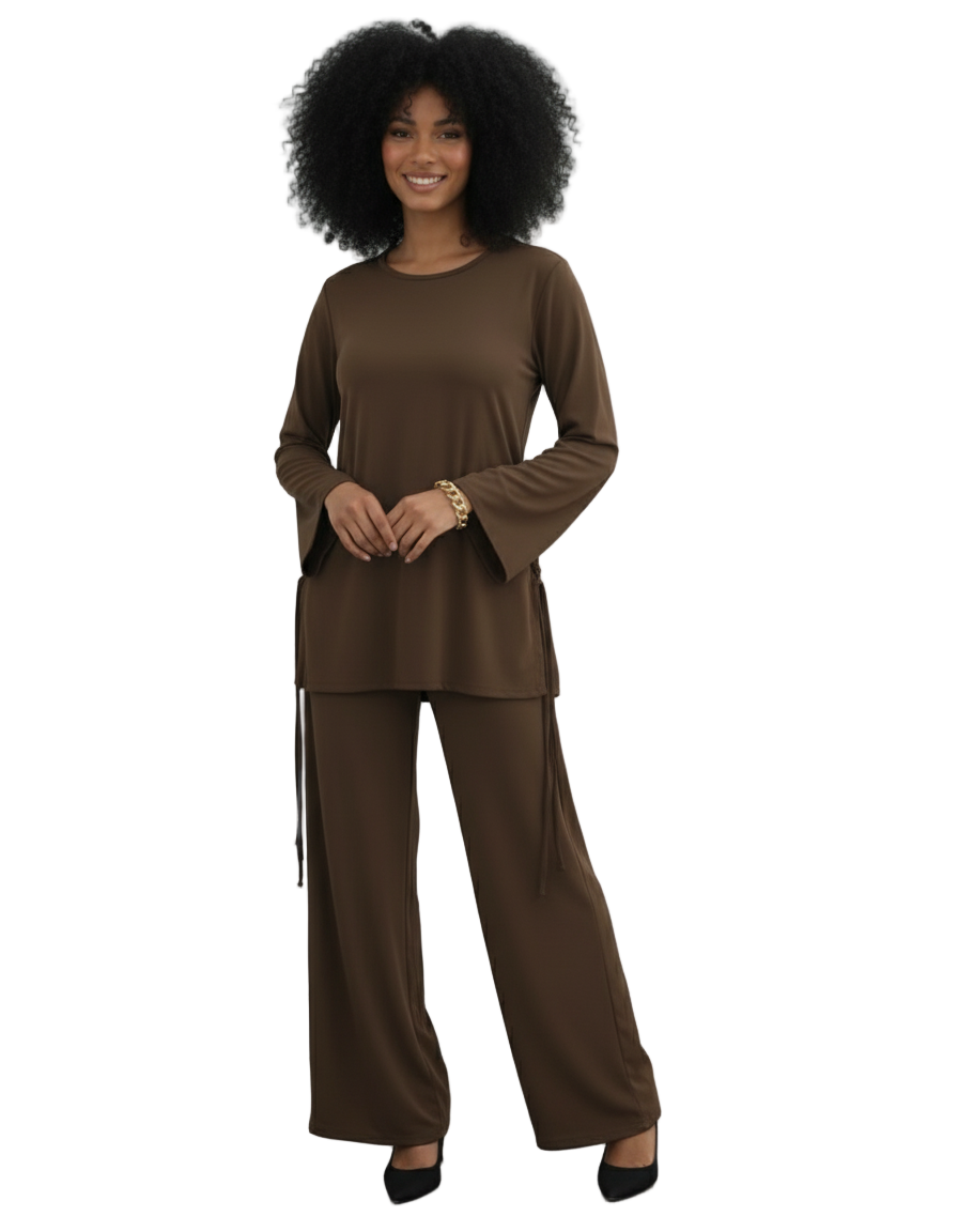 Woman wearing a brown outfit standing against a white paneled wall.