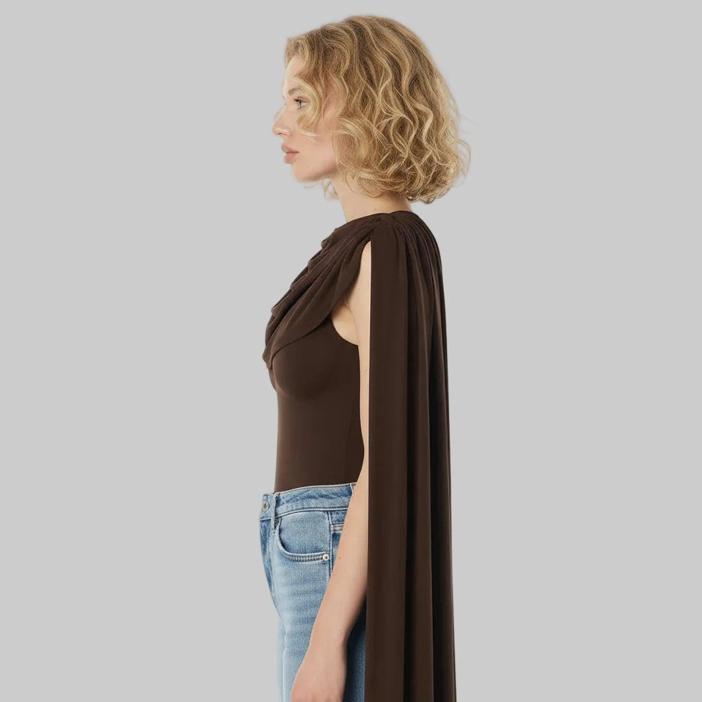Woman wearing a brown top with a cape over one shoulder on a white background