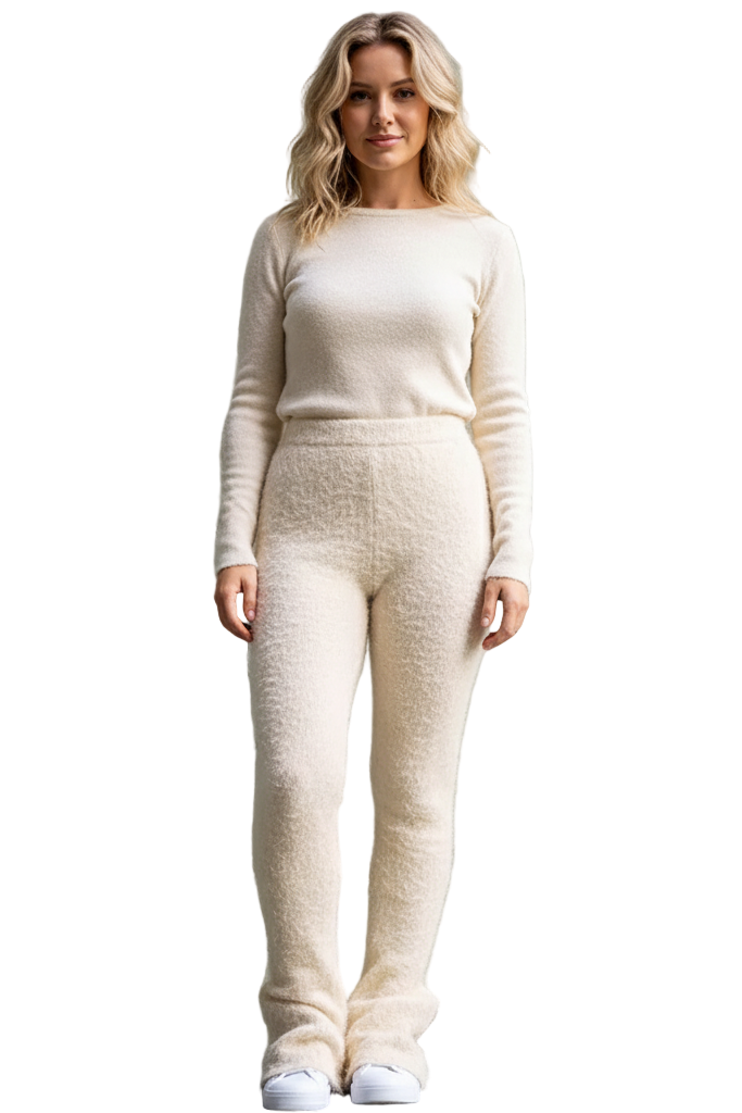 Woman wearing a cream-colored outfit standing against a plain wall.