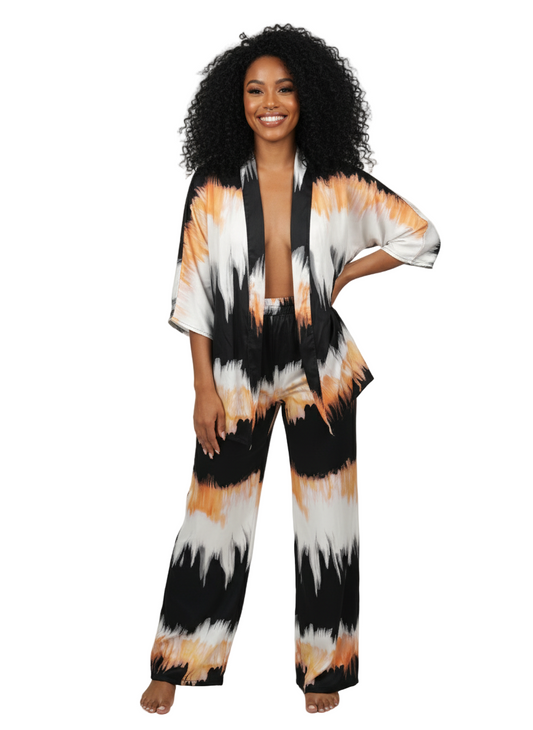 Woman wearing a tie-dye outfit with black, orange, and white patterns on a plain background