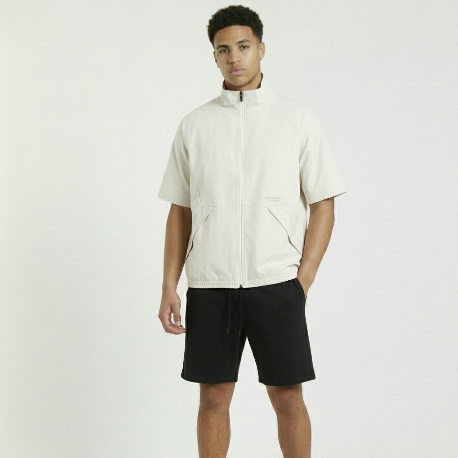 Man wearing a beige jacket and black shorts on a white background