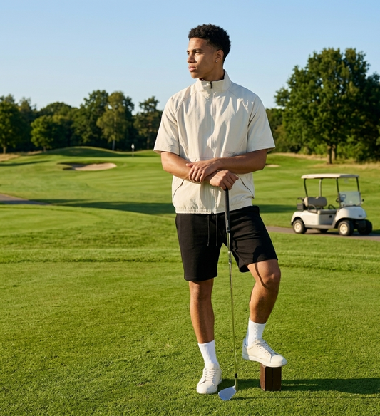 Man on a golf course holding a golf club with a golf cart in the background