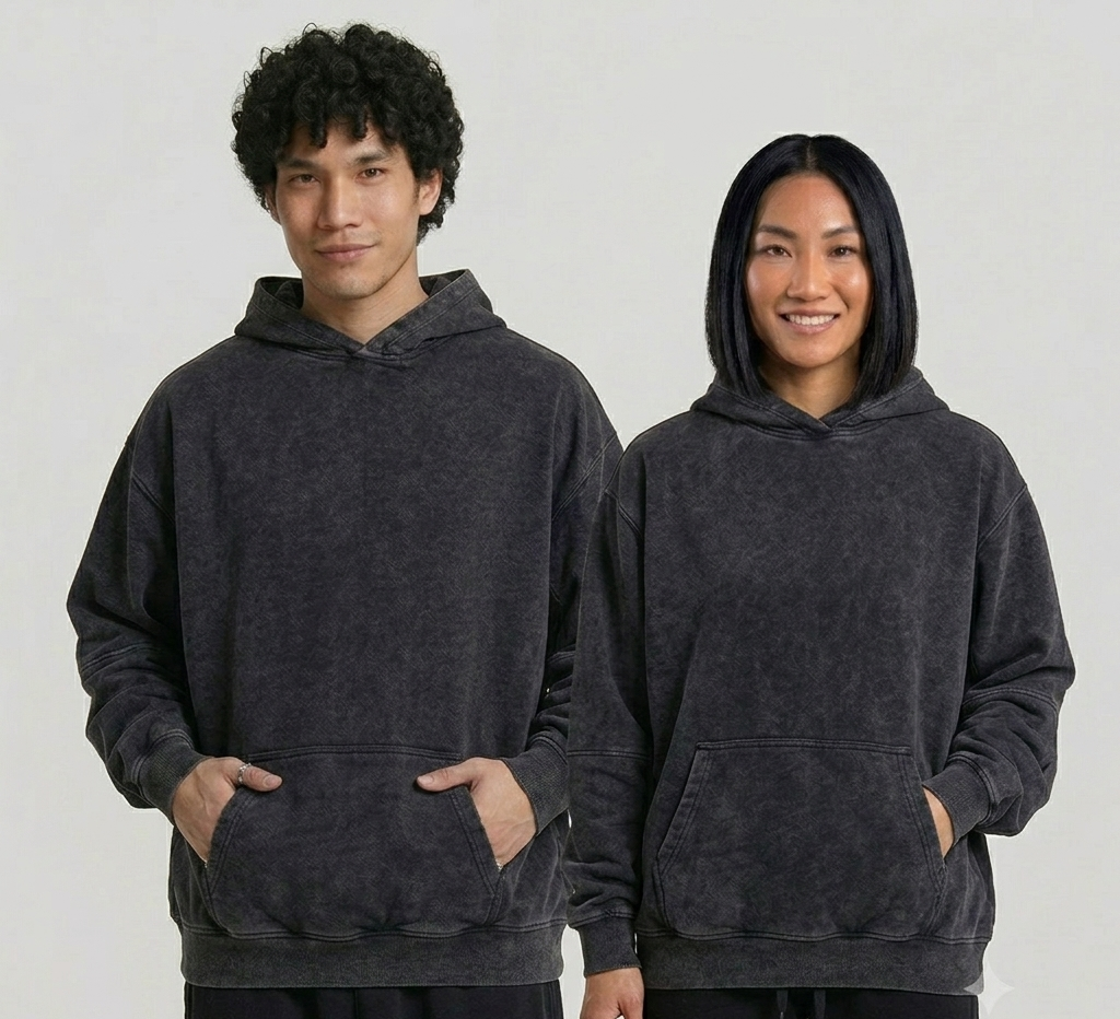 Two people wearing dark gray hoodies on a plain background