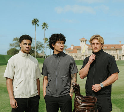 Three men standing on a golf course with a golf bag and balls.