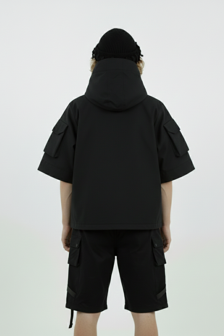 Person wearing a black hooded jacket and shorts on a white background
