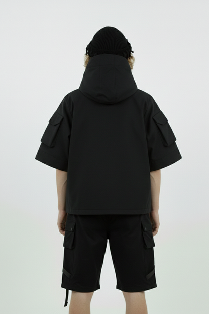 Person wearing a black hooded jacket and shorts on a white background